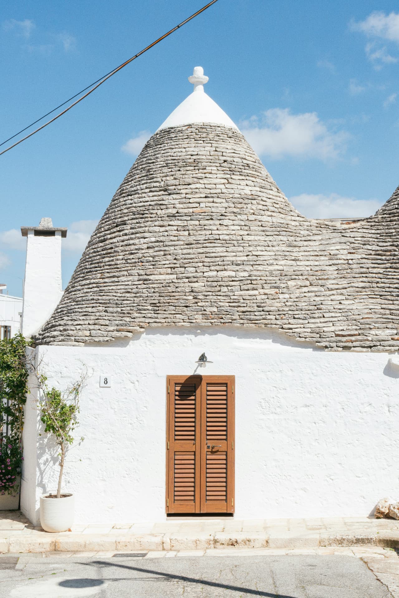 A whitewashed trullo with a conical dry-stone roof in Puglia, Italy
